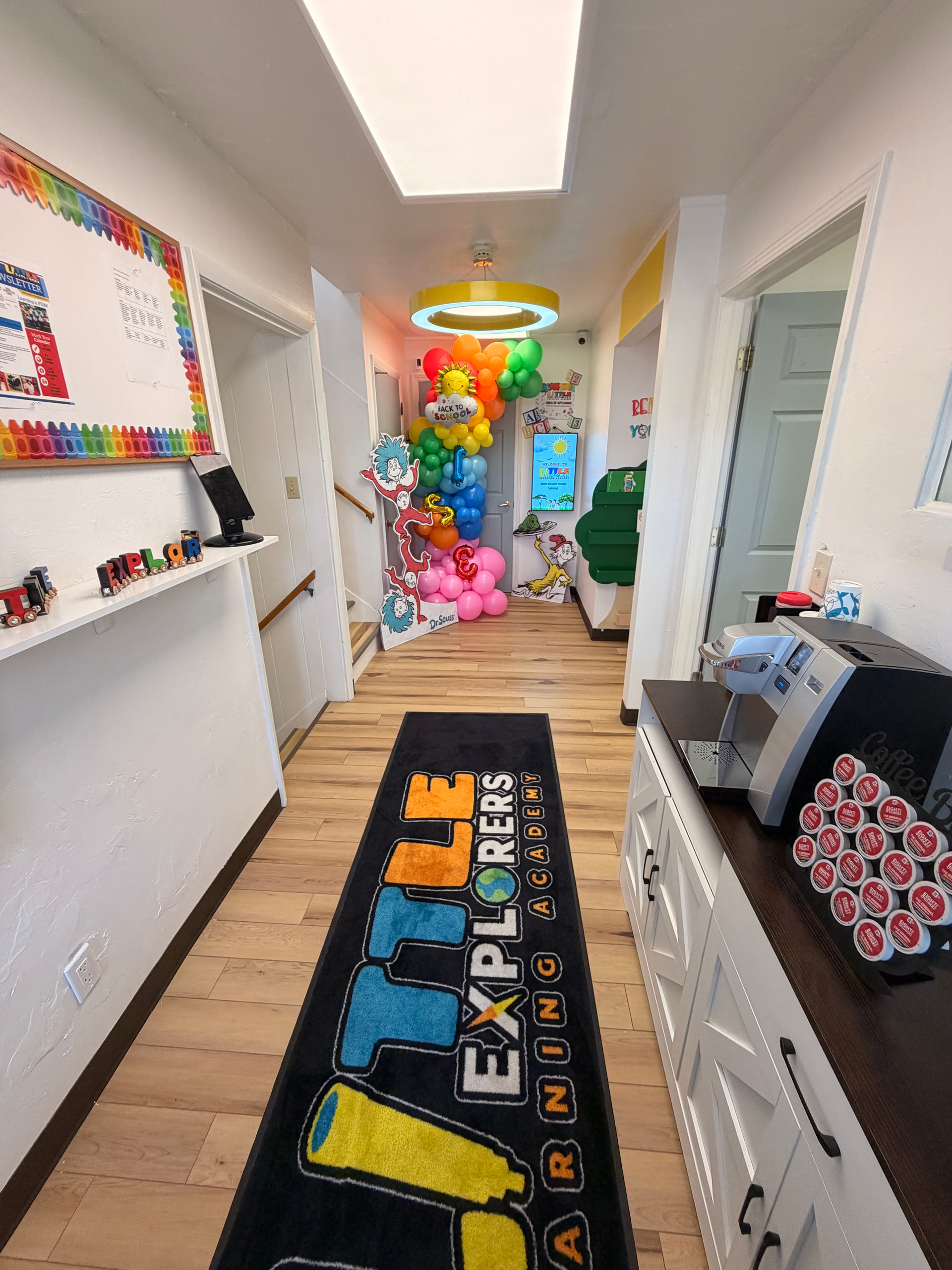 The hallway at Little Explorers Learning Academy, with the school name on a long floor runner leading toward the rooms